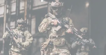 Armed military personnel with rifles and communication devices carrying out a mission in an urban setting while wearing tactical gear.