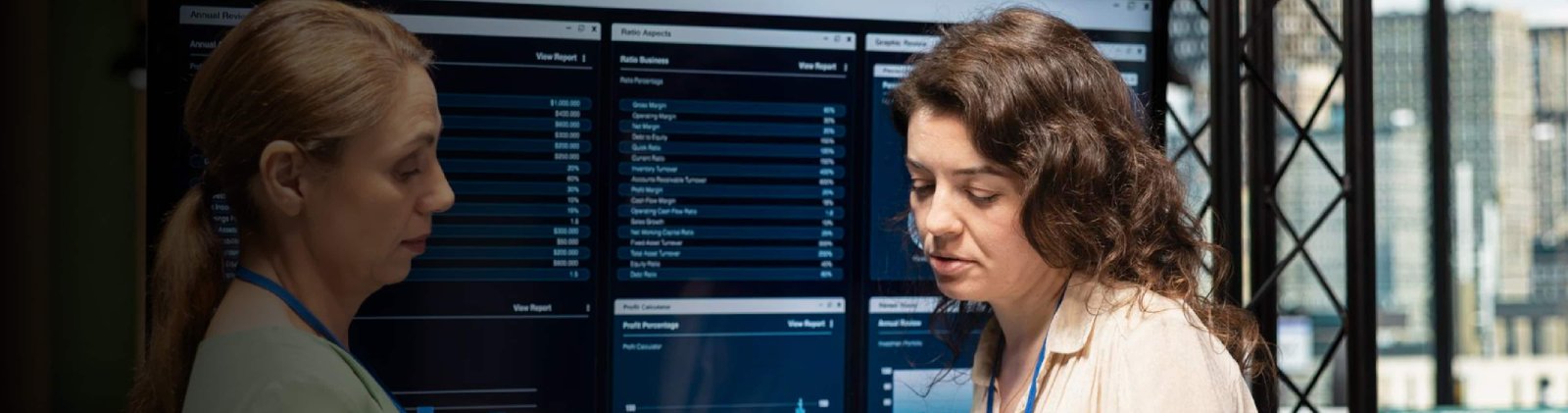 Two professionals collaborating while reviewing data on computer screens