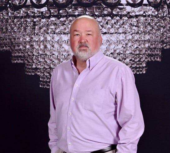 Portrait of a senior male professional standing against a patterned background