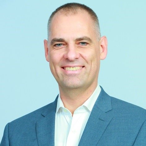 rofessional headshot of a smiling male team member in a teal blazer