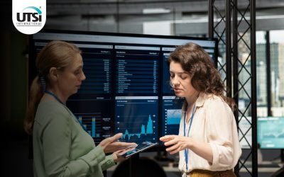 Two professionals collaborating while reviewing data on computer screens